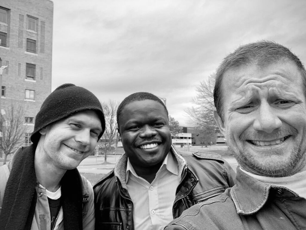 Severin (in center) taking a selfie with two men (one on each side) during the first outreach in downtown St. Louis.