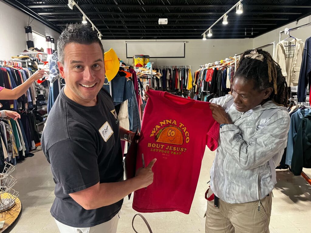 an inExcelsis staff (Matt-on the left) holding a read t-shirt with a happy guest (on the right) she just got from inExcelsis boutique.