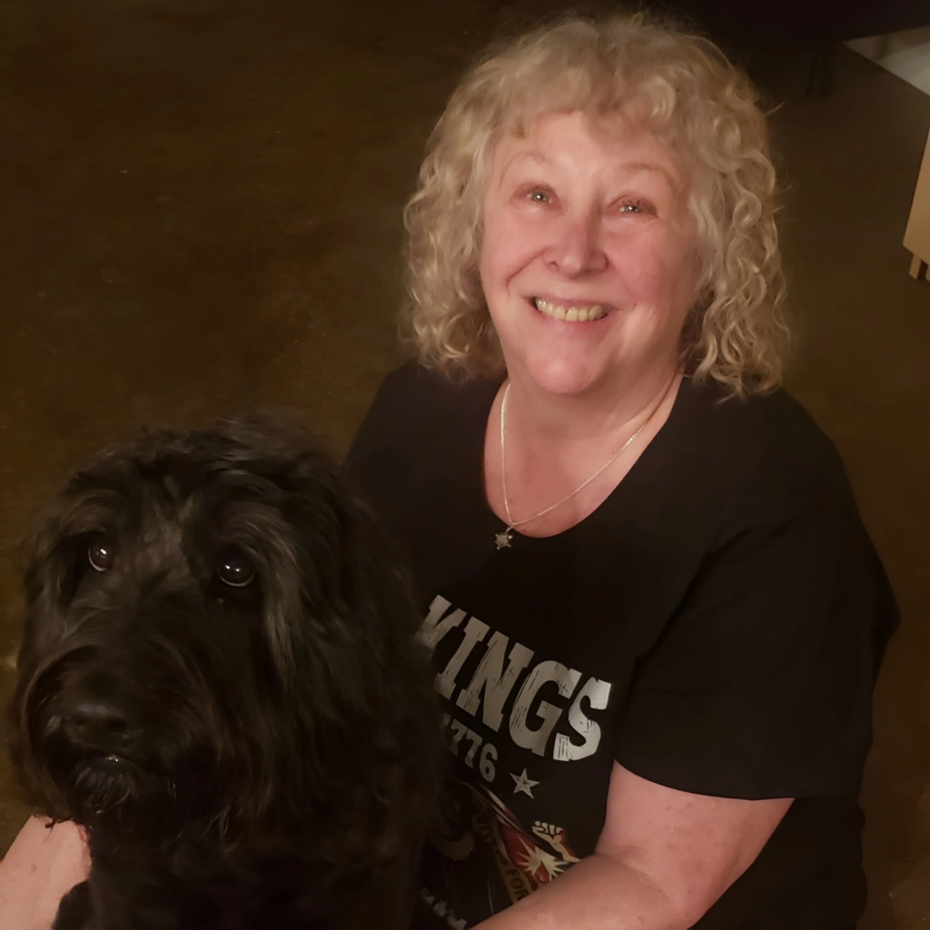 Nancy Mack sitting with her black poodle noodle dog.