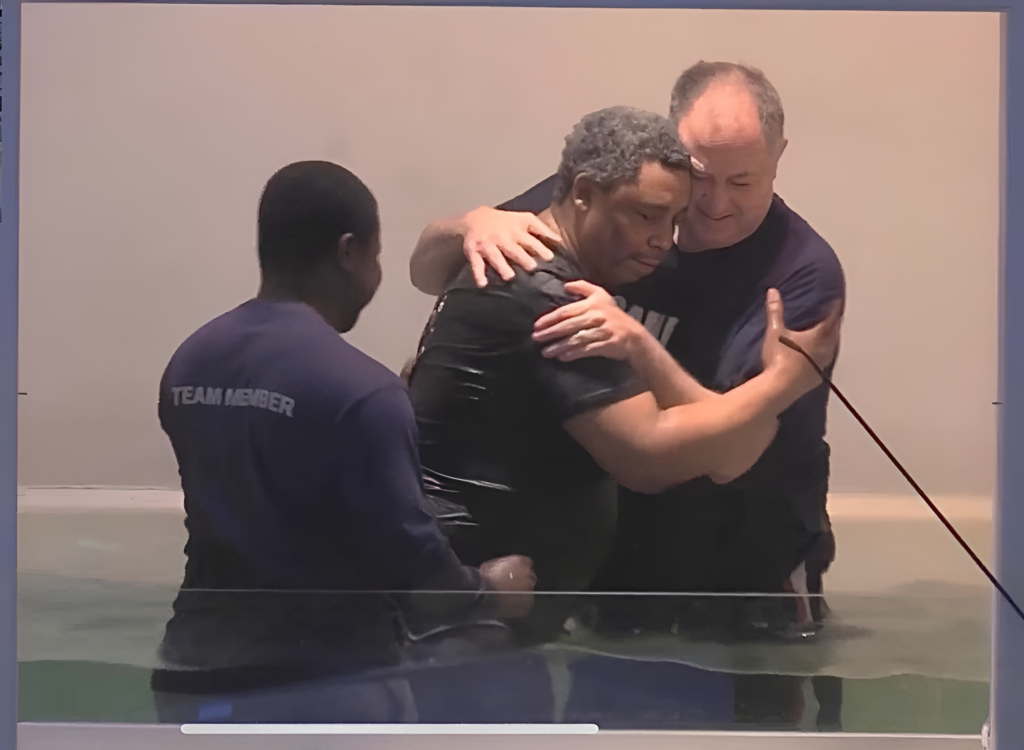 Severin Pelekara (left) Pastor Mike Priest (right) hugging Cornelius(center) in the baptismal pool.