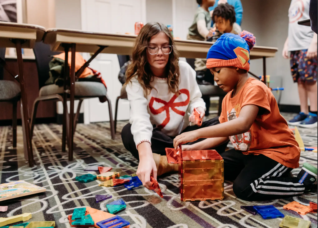inExcelsis volunteer playing with a boy, one of the participants on the carpet during winter safe haven 2026.